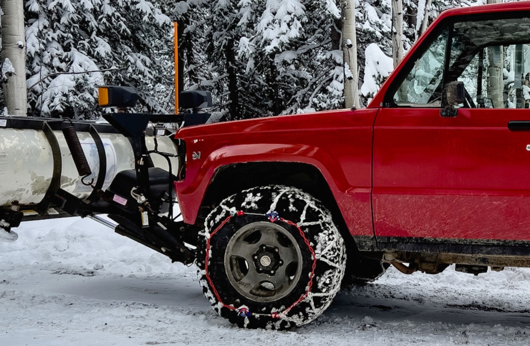Mill Creek Snow Removal's plow blade and chained tire in fresh snow